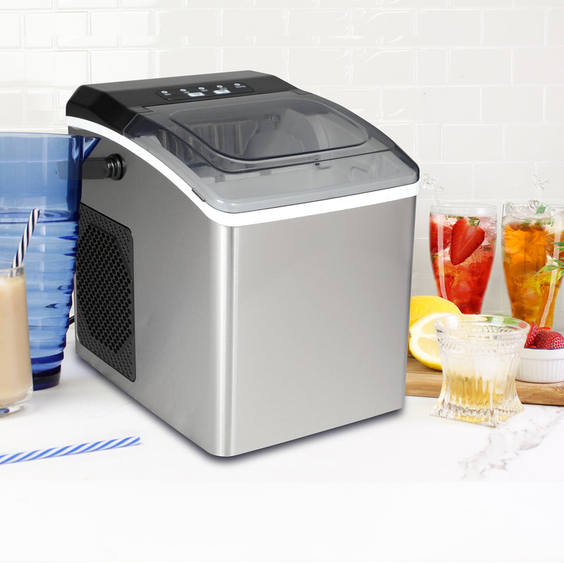 Stainless steel ice maker on a white countertop with white tile backsplash behind and glasses of juice, iced tea, water, and iced coffee on either side