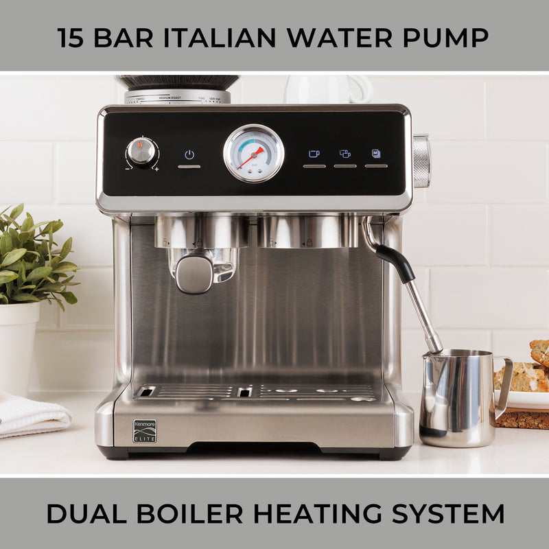 Kenmore Elite auto-tamping espresso machine and stainless steel milk frothing jug on a white counter with a white tile backsplash behind. Text above reads, "15 bar Italian water pump," and text below reads, "Dual boiler heating system."